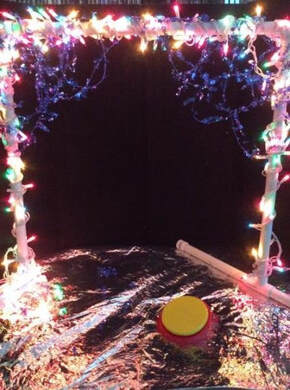 PVC toy bar wrapped in lights on a reflective emergency blanket with a switch to activate the lights